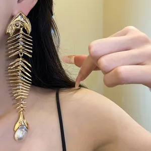 Detailed view of oversized vintage gold fishbone earring with pearl drop on model shoulder