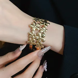 Detail view of an elegant gold double-layered flower open cuff bracelet on a wrist