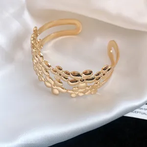 Close-up view of a vintage gold double-layer floral open bangle resting on white satin