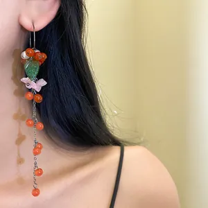 Detailansicht eines langen Quastenohrrings mit Harzblume, grünem Blatt und Perlen