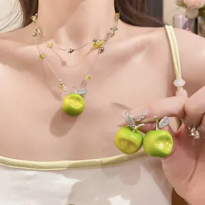 Close-up of double-layered beaded necklace and green resin apple earrings with zircon