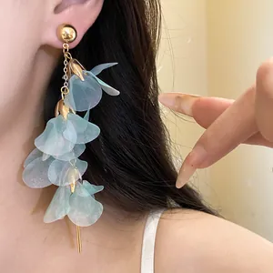 Detailed close-up of light blue mesh petal tassel earrings worn by a model in a studio