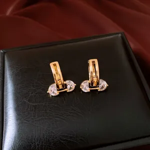 Close-up of 18K gold plated hollow earrings with sparkling zirconia inlay detail.