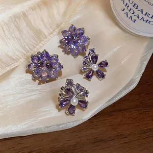 Elegante paarse zirkoon bloem oorklemmen en parel vlinder oorbellen op zijden stof