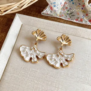 Detailed view of 14k gold plated ginkgo leaf earrings with zircon accents.