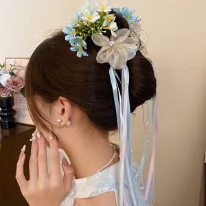 Close-up of ballet style hair clip featuring blue flowers and long pastel ribbons on a bun