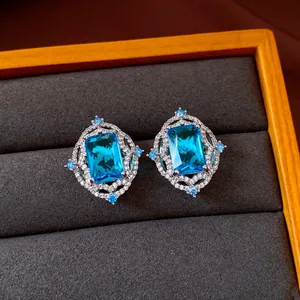 Close-up of vintage palace style earrings with radiant blue emerald-cut zircon stones.