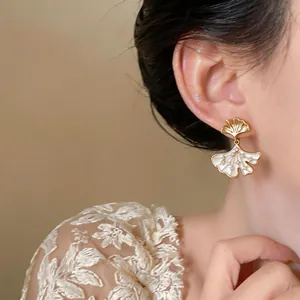 Detailed view of elegant 14k gold plated ginkgo leaf earrings with zircon on model