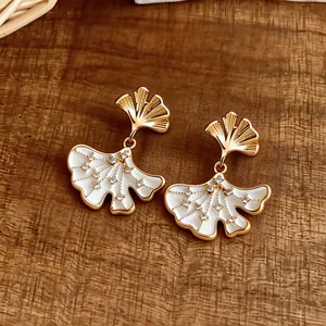 Detailed view of gold-plated ginkgo leaf earrings with white inlay and zircon stones