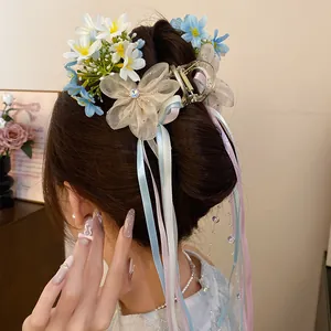 Detailed back view of a balletcore flower hair clip with long blue and pink ribbons on a bun