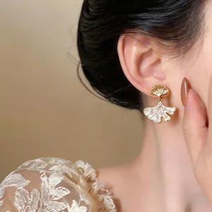 Detailed view of 14k gold-plated ginkgo leaf earrings with sparkling zircon on ear