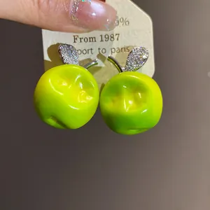 Detail view of sweet forest style green resin apple earrings with sparkling zircon leaves