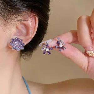 Gedetailleerde close-up van elegante paarse zirkoon bloem oorclips op een model