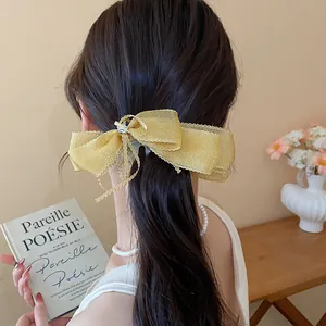 Vista detallada de un elegante lazo dorado brillante en el cabello oscuro ondulado del modelo