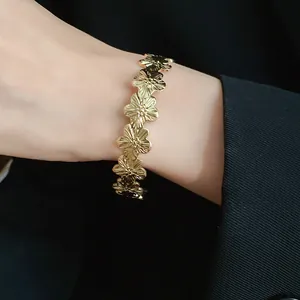 Close-up of a vintage-style gold metal open bangle with a floral flower design