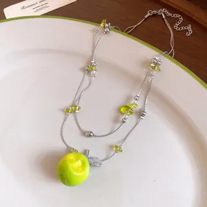 Detailed macro view of double-layered beaded necklace with a vibrant green resin apple pendant