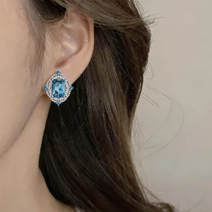 Close-up detail of a vintage court style blue square zircon stud earring worn on the ear