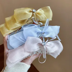 Detalle de tres elegantes pinzas para el cabello con lazo de encaje y pedrería en tonos.