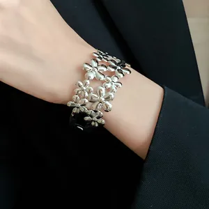 Detailed view of a silver double-layered floral cuff bracelet styled on a wrist for fashion.