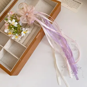 Detail of ballet style hair clip with pink organza flower and long colorful ribbons