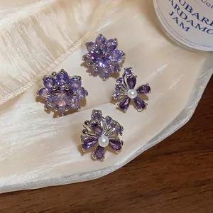 Gedetailleerde weergave van elegante paarse zirkoon bloem oorclips met witte parels.