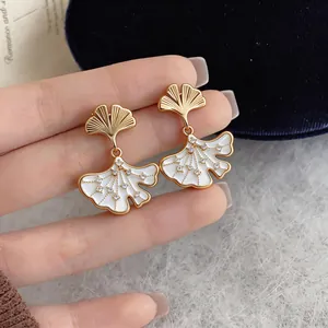 Close-up of elegant ginkgo leaf earrings with 14k gold plating and sparkling zircons