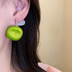 Close-up detail of a green resin apple earring with a sparkling zircon leaf decoration