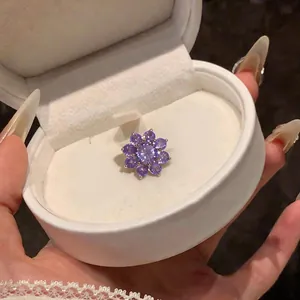 Detailopname van een paarse zirkoon bloem oor cuff in een witte sieradendoosje.