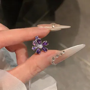Detailopname van een paarse zirkoon bloem ear cuff met een parel