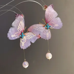 Detalle de pendientes de mariposa morados translúcidos con gota de perla irisada