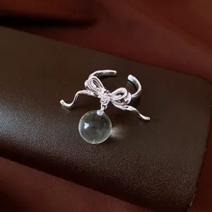 Close-up detail of silver bow ring with zircon center and clear resin sphere pendant