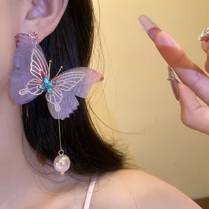 Detalle de pendiente de mariposa púrpura brillante con cristal azul y una perla rosada