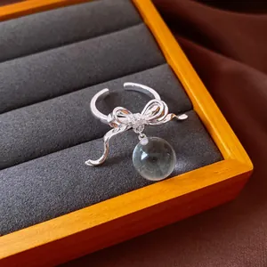Macro view of an elegant silver bow ring featuring a translucent round resin charm
