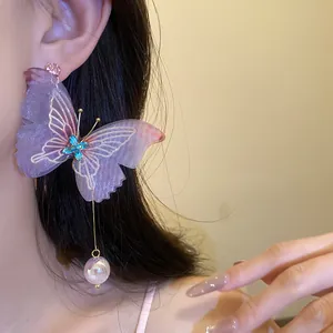 Vista detallada de elegantes pendientes de mariposa morados con colgante de perla en modelo