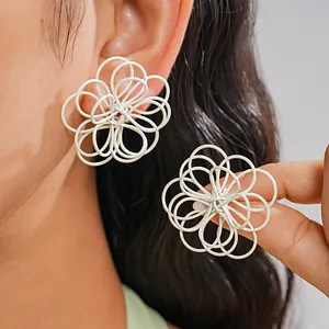 Detalle de pendientes de flores blancas caladas con diseño entrelazado y pintura