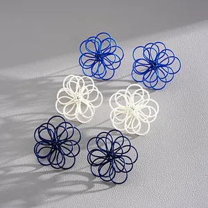 Macro de pendientes de flores huecas pintadas en tonos azul, blanco y marino