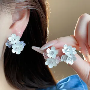 Detail of white enamel flower earrings with sparkling zirconia stones.