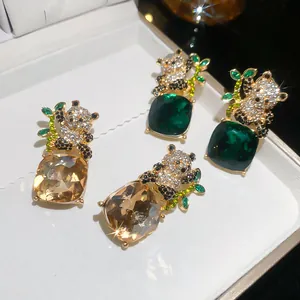 Detalle de pendientes de panda con diamantes y piedras de color verde y champán