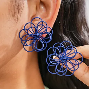 Primer plano de pendientes de botón de flor de alambre azul de gran tamaño en el lóbulo