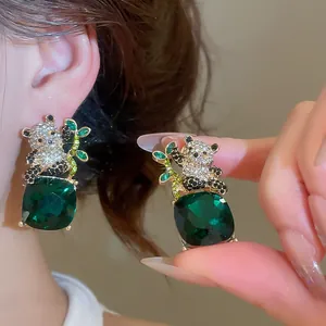 Detalle de pendientes de panda con piedras verdes cuadradas y brillantes de diamantes.