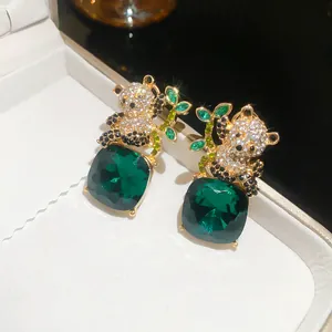 Detalle de pendientes de panda brillantes con grandes piedras verdes de corte cuadrado
