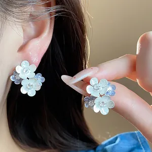 Close-up detail of multi-layered floral earrings with zircon centers and oil-drop petals.