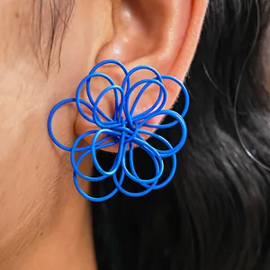 Primer plano detallado de un elegante pendiente de flor azul calada puesto en la oreja