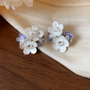 Detailed view of floral stud earrings with white and purple enamel petals and zircons