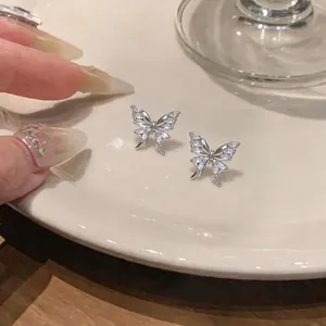 Detailed macro view showing silver-colored butterfly stud earrings inlaid with marquise zircons