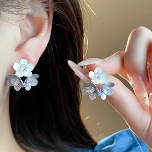 Close-up of elegant triple flower stud earrings with zircon and white enamel detail