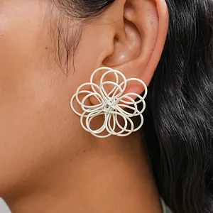 Primer plano de pendientes de flores blancas caladas y entrelazadas en la oreja.