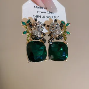 Detalle de pendientes de panda con grandes piedras cuadradas de color verde esmeralda