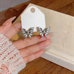 Detailed close-up of sparkling zircon butterfly stud earrings on a display card