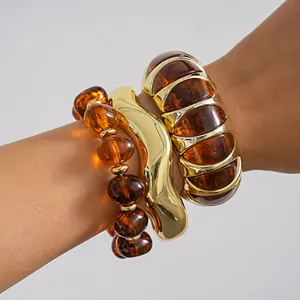 Macro detail of retro amber acrylic beaded bracelet and gold wavy cuff jewelry set